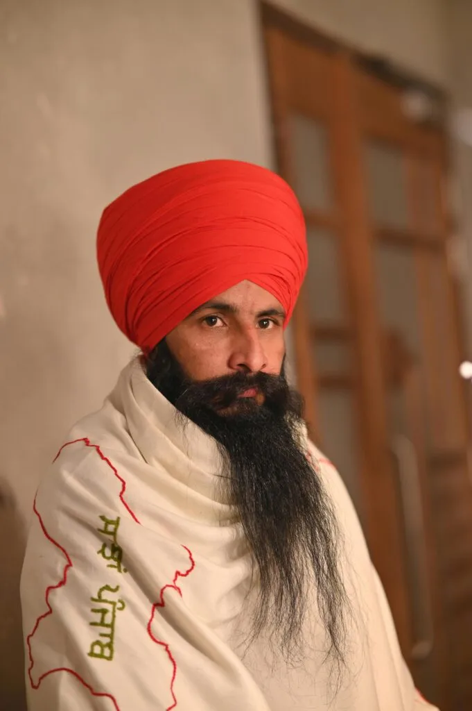 Portrait of a Sikh man in traditional clothing and red turban in Barnala, India.